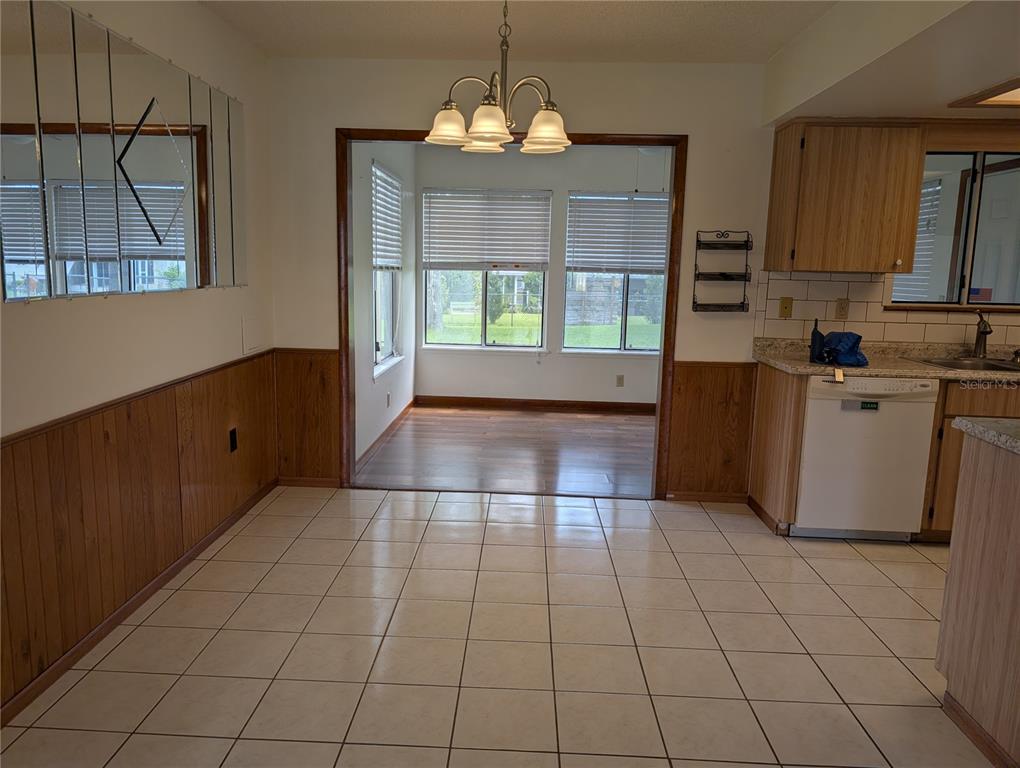 A dining area with tiled floors, wood wainscoting, and a doorway leading to a sunroom — 10881 SW 78TH COURT, OCALA, FL