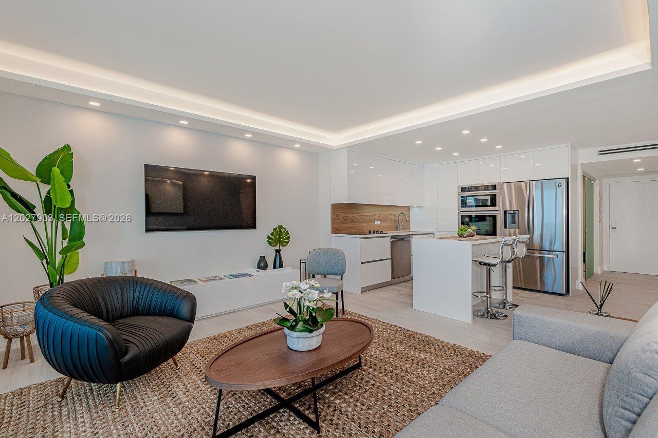 A modern open-concept living room features a kitchen island, stainless steel appliances, and wood flooring — 2301 Collins Ave # 739, Miami Beach FL 33139, MIAMI BEACH, FL