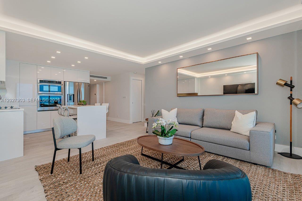 A modern living room features a grey sofa, a coffee table, and an open kitchen — 2301 Collins Ave # 739, Miami Beach FL 33139, MIAMI BEACH, FL