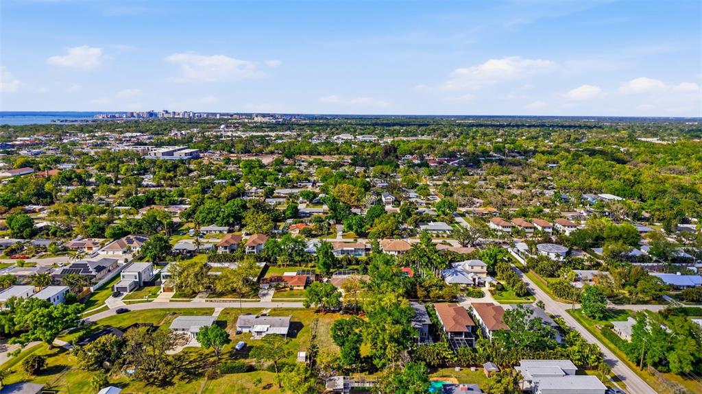 An aerial view shows a suburban neighborhood with many trees and houses near the coast — 2320 FLORINDA STREET, SARASOTA, FL