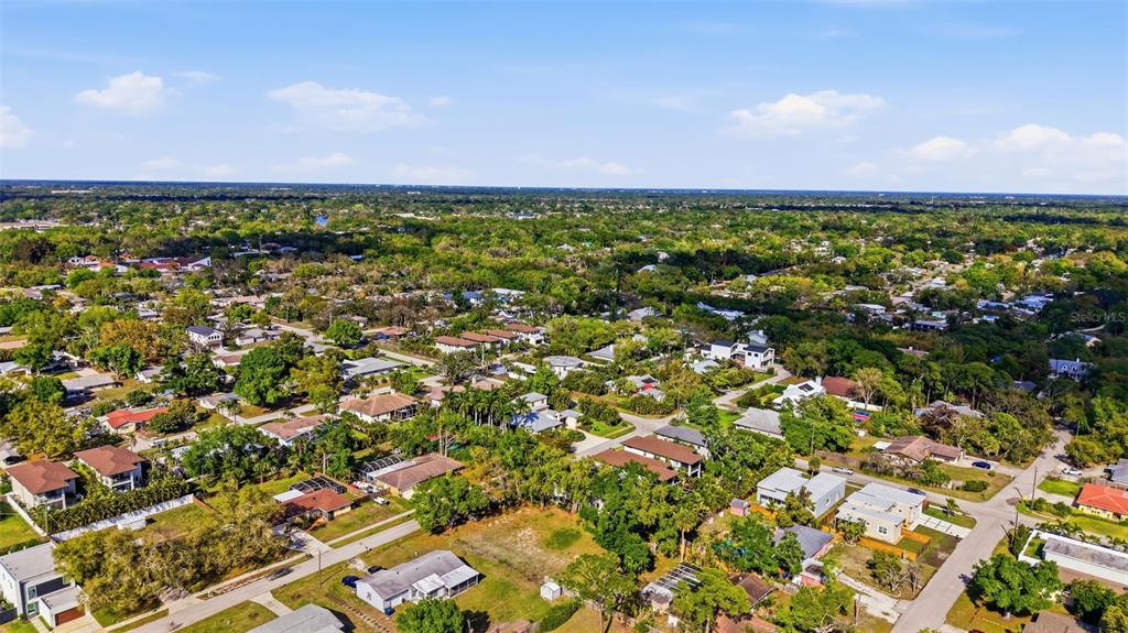 An aerial view shows a suburban neighborhood with many trees and houses under a blue sky — 2320 FLORINDA STREET, SARASOTA, FL