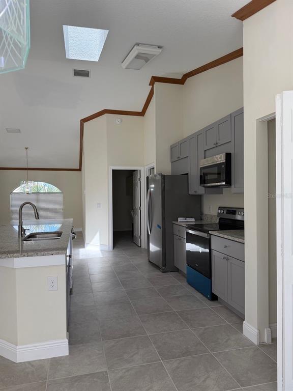 A kitchen features gray cabinets, stainless steel appliances, granite countertops, and tile flooring — 4572 NW 32ND STREET, OCALA, FL