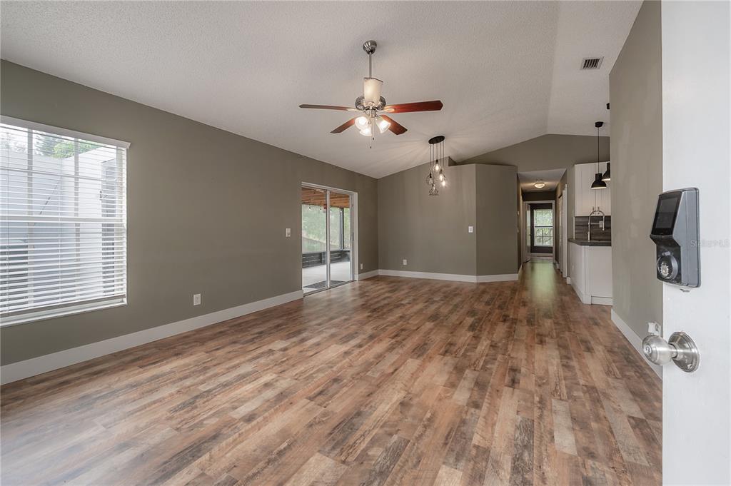 A living room with wood-look flooring, gray walls, a ceiling fan, and a sliding glass door — 2756 BRAHAM COURT, PALM HARBOR, FL