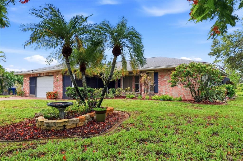 A single-story brick house with a palm tree garden and a birdbath in the front yard — 1175 CAPLES STREET, ENGLEWOOD, FL