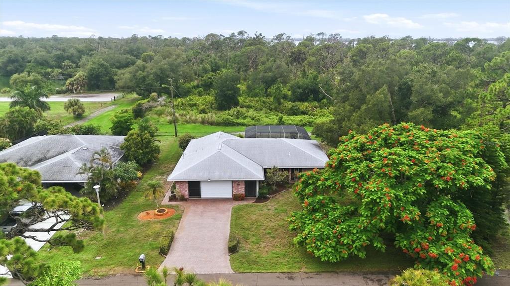 An aerial view of a single-story house with a brick driveway and a large flowering tree — 1175 CAPLES STREET, ENGLEWOOD, FL