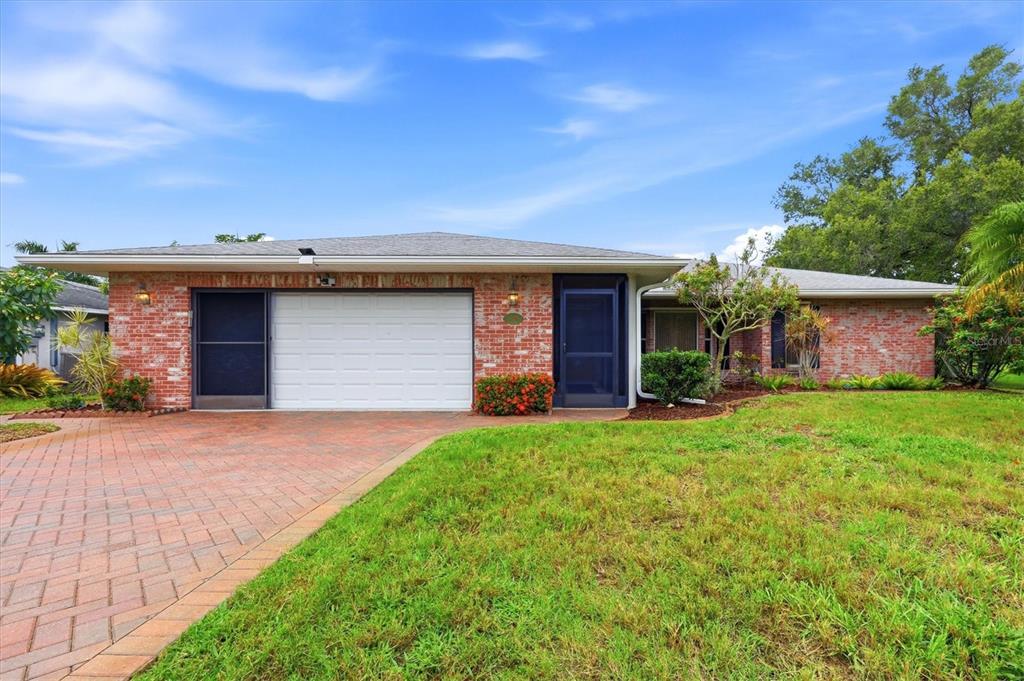 A single-story brick house with a white garage door and a paved driveway — 1175 CAPLES STREET, ENGLEWOOD, FL