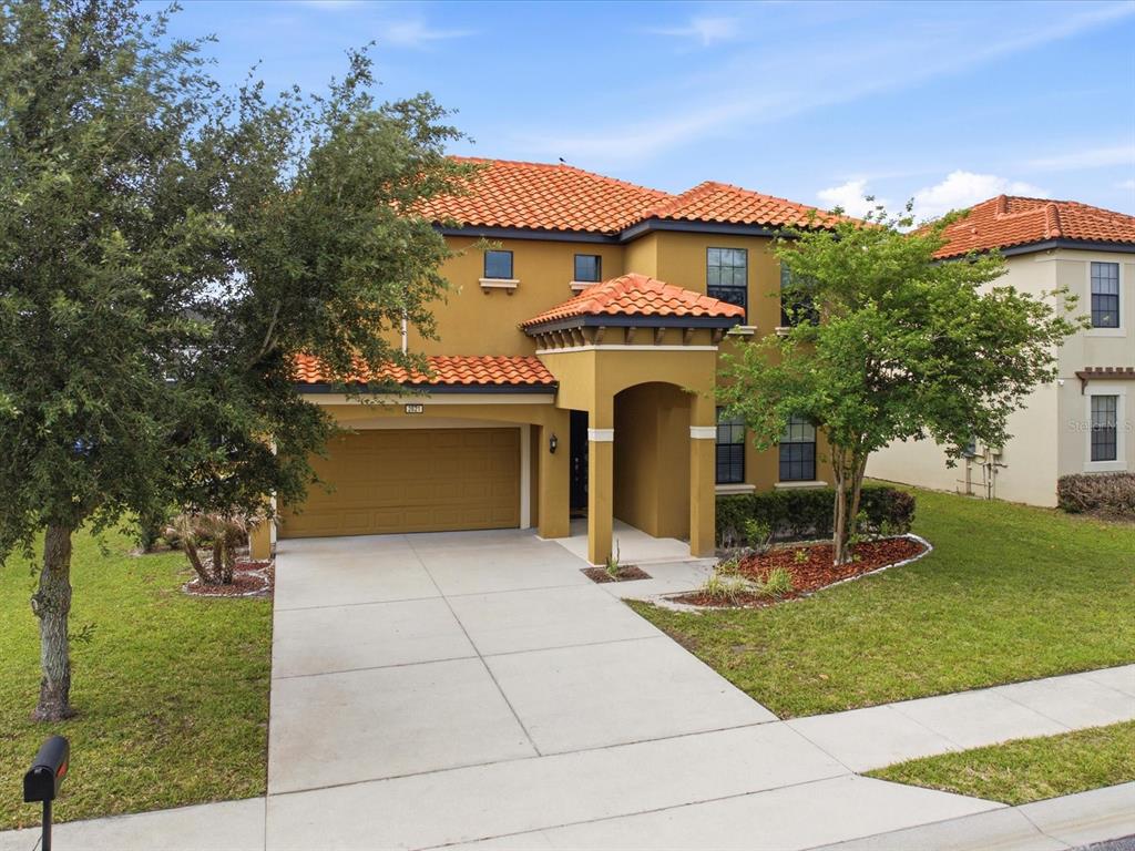A two-story house with a tan stucco exterior, orange tile roof, and a two-car garage — 2621 ROSEMONT CIRCLE, DAVENPORT, FL