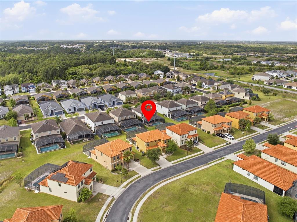 An aerial view shows a suburban neighborhood with many houses featuring swimming pools and screened lanais — 2621 ROSEMONT CIRCLE, DAVENPORT, FL