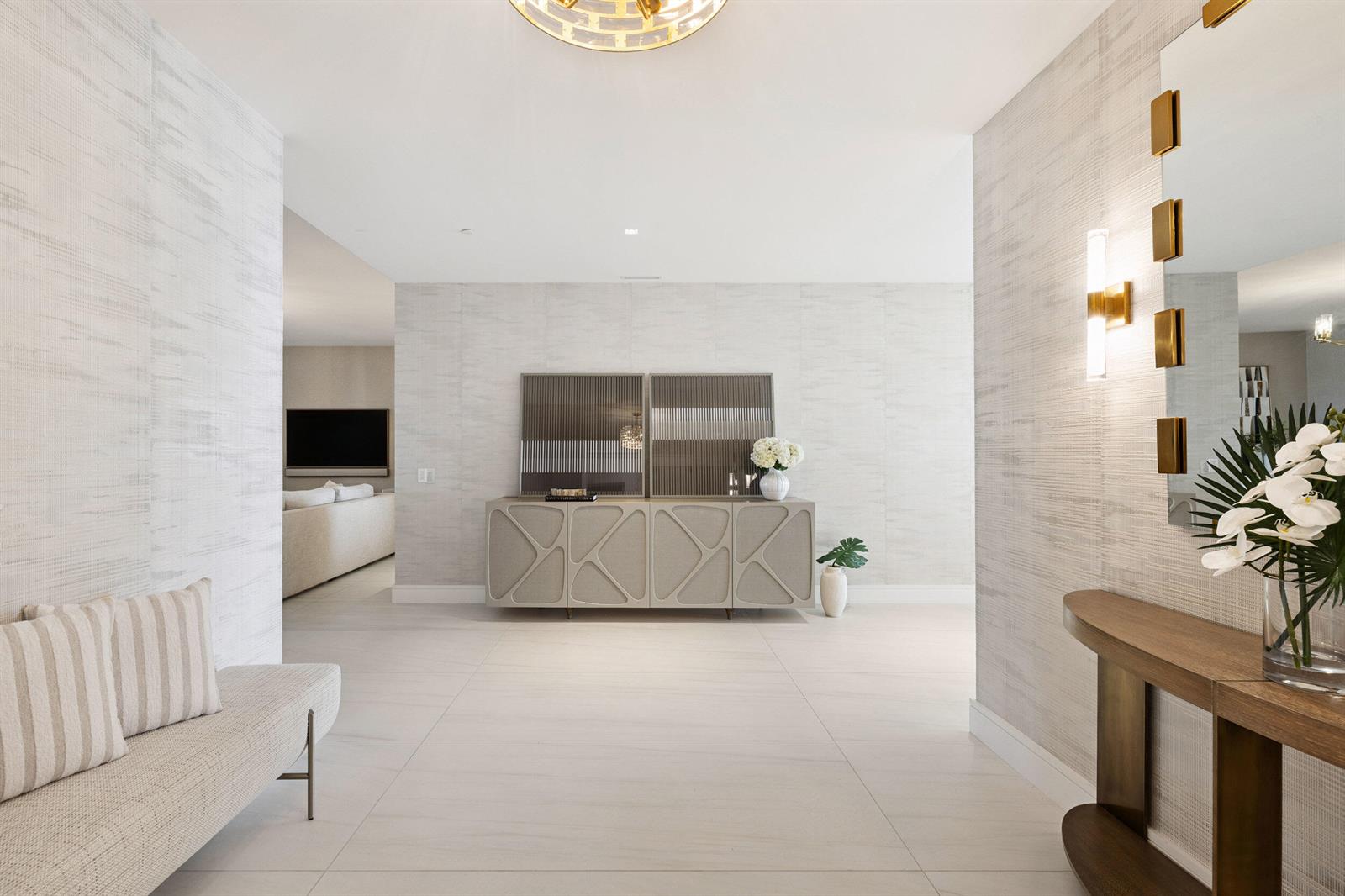 A bright entryway features textured wallpaper, a modern console table, and a bench on tile flooring — 725 S Ocean Boulevard # 402, Boca Raton FL 33432, BOCA RATON, FL