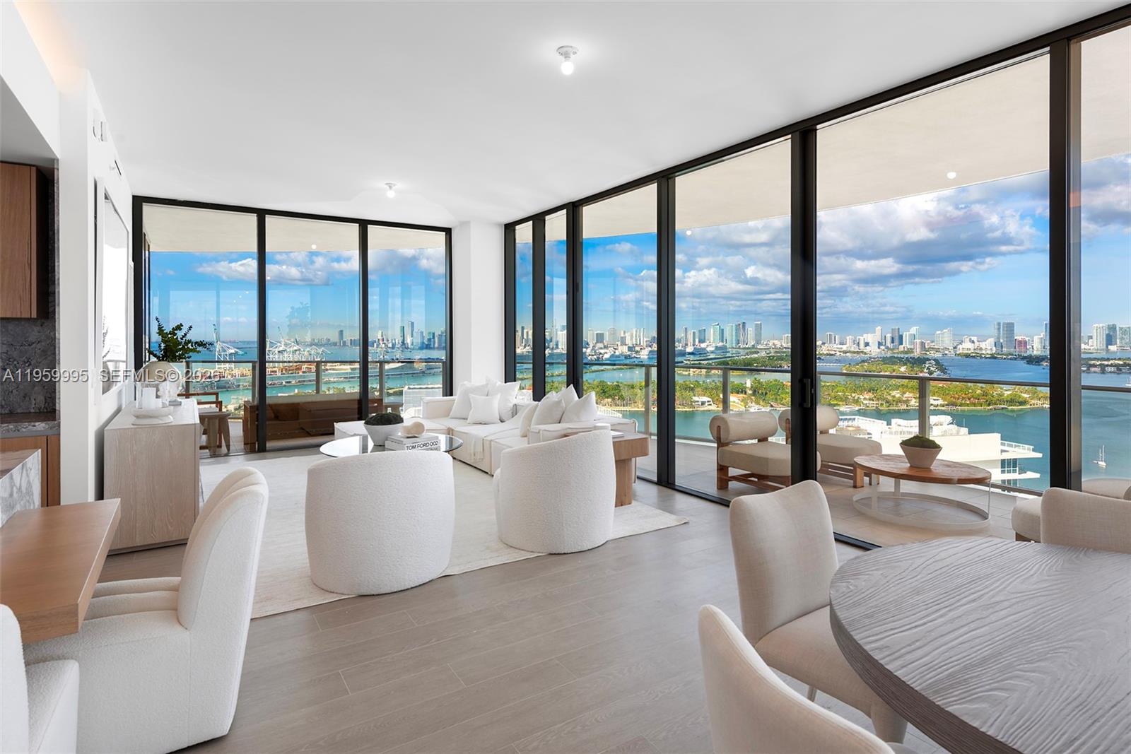 A balcony with a round wooden table and wicker chairs overlooks a city skyline at dusk — 500 Alton Rd # 2903, Miami Beach FL 33139, MIAMI BEACH, FL