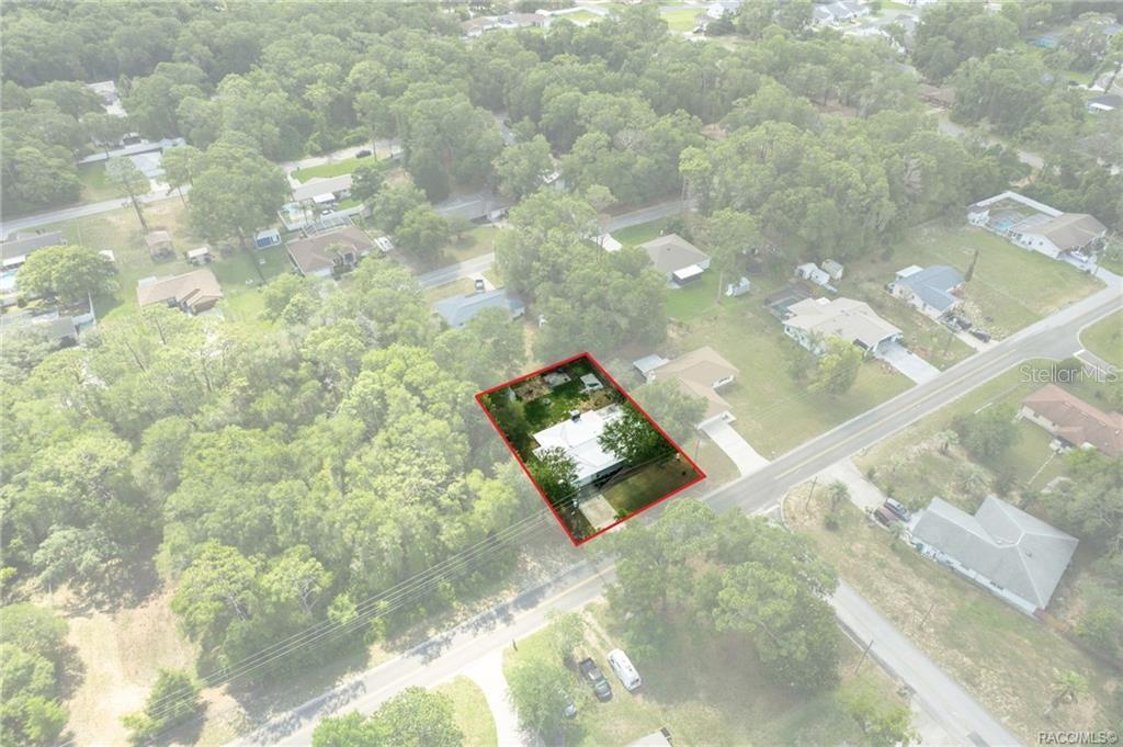 An aerial view shows a single-story house with a white roof on a wooded lot — 1140 S HIGHLANDS AVENUE, INVERNESS, FL