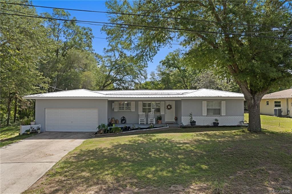 A single-story gray house with a white brick base, metal roof, and attached garage — 1140 S HIGHLANDS AVENUE, INVERNESS, FL