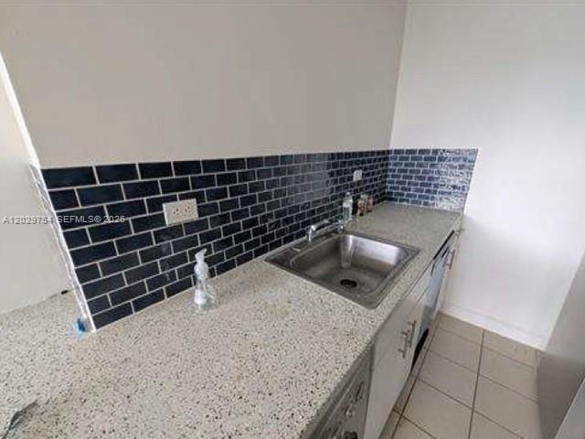 A kitchen counter features a stainless steel sink, speckled granite countertops, and dark subway tile — 1500 Bay Rd # 310S, Miami Beach FL 33139, MIAMI BEACH, FL