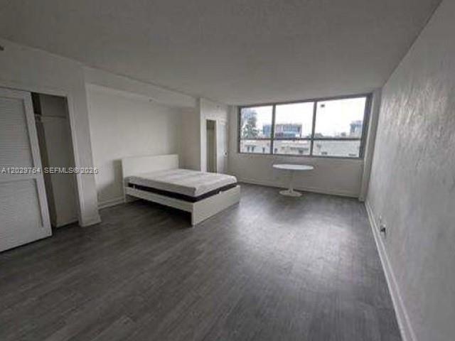A bedroom with gray wood-look flooring, a white bed frame, and a large window — 1500 Bay Rd # 310S, Miami Beach FL 33139, MIAMI BEACH, FL