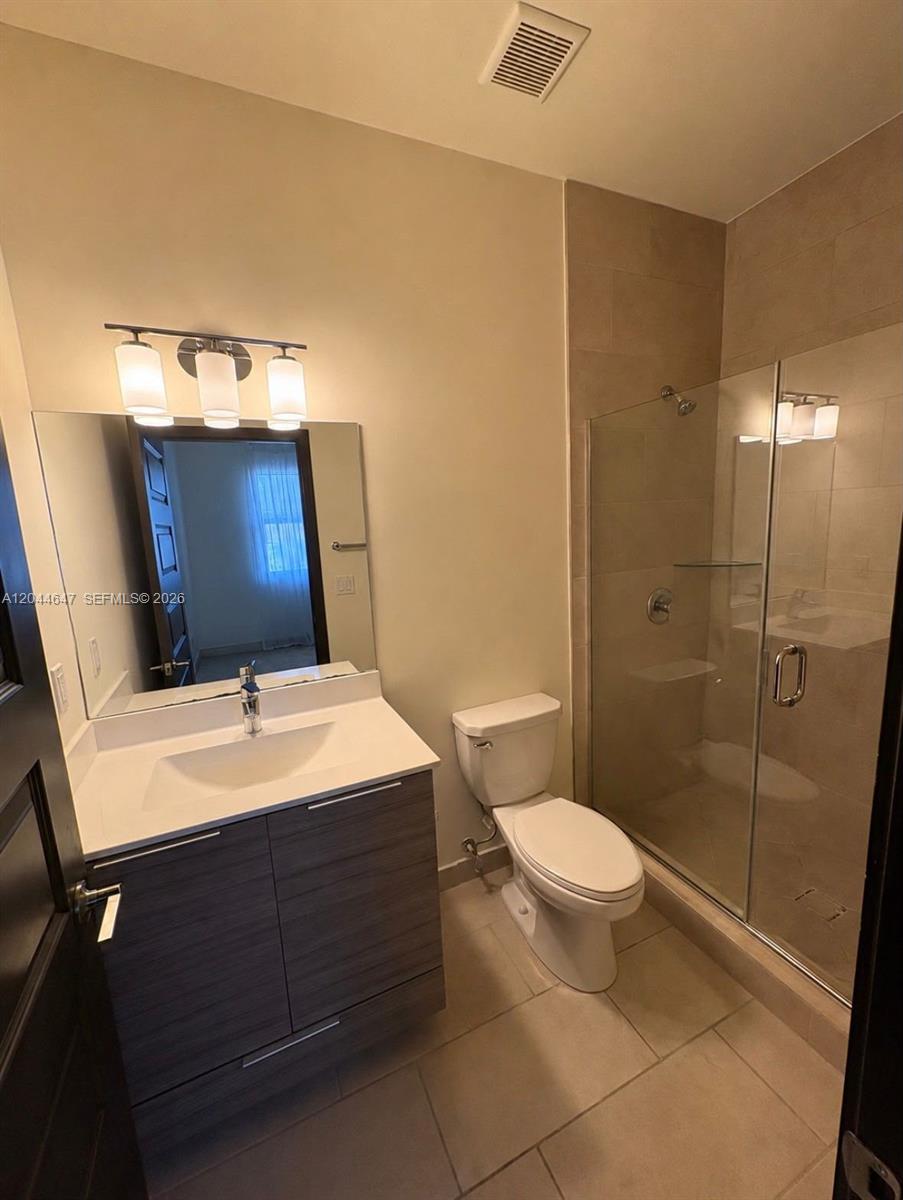 A bathroom features a vanity with a white countertop, a toilet, and a glass-enclosed shower — 15668 NW 91st Ct, Miami Lakes FL 33018, MIAMI LAKES, FL