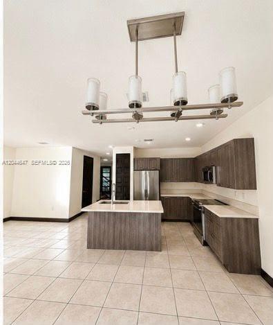 A kitchen with dark wood cabinets, a central island, and a modern linear chandelier — 15668 NW 91st Ct, Miami Lakes FL 33018, MIAMI LAKES, FL