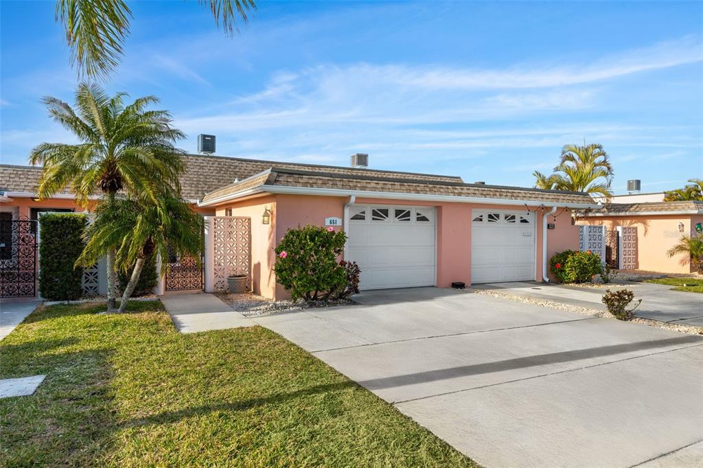 A peach-colored single-story house features two white garage doors and a palm tree out front — 651 BOCA CIEGA POINT BOULEVARD S, ST PETERSBURG, FL