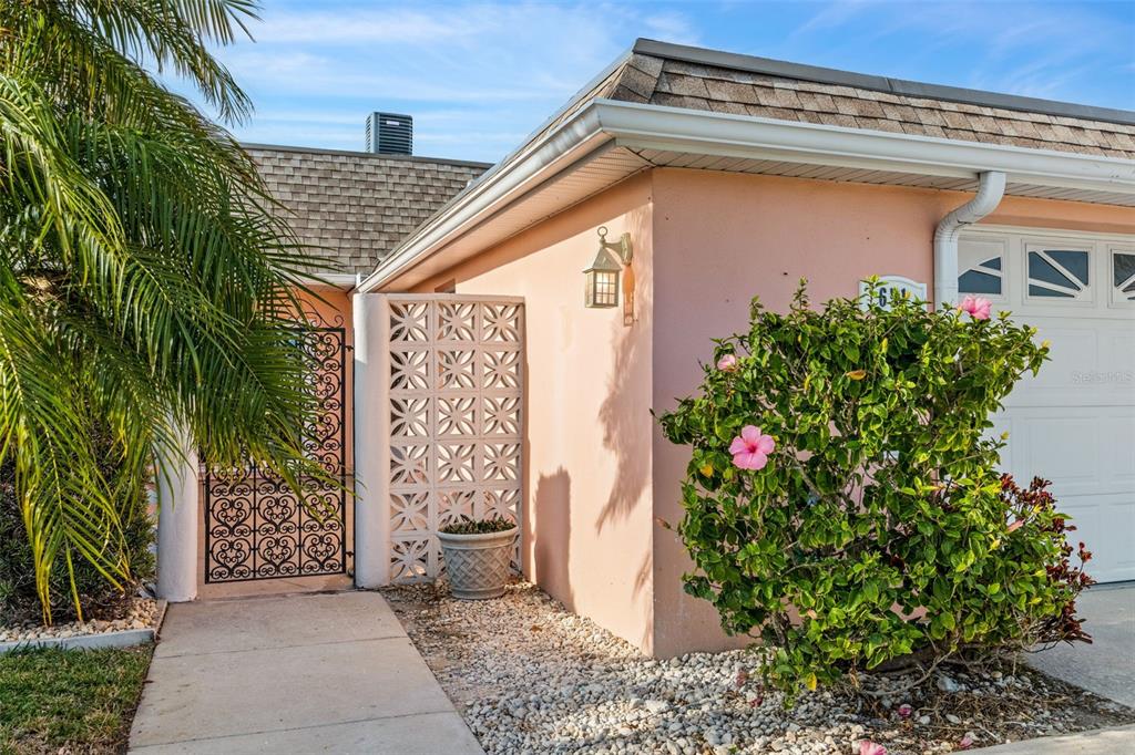 A pink stucco house exterior features a decorative screen wall, a palm tree, and landscaping — 651 BOCA CIEGA POINT BOULEVARD S, ST PETERSBURG, FL