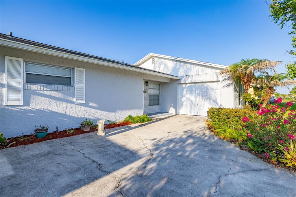 The exterior of a single-story house features a concrete driveway, a garage, and landscaping — 708 WEDGE LANE, POINCIANA, FL