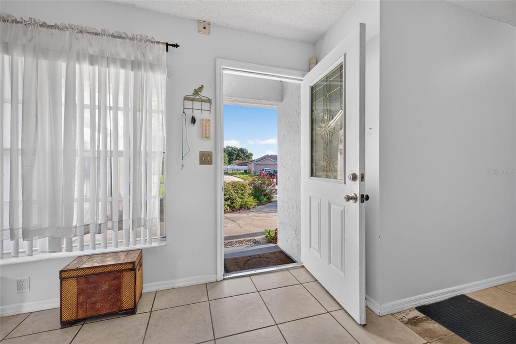An entryway with tile flooring, a white front door, and a window with sheer curtains — 708 WEDGE LANE, POINCIANA, FL