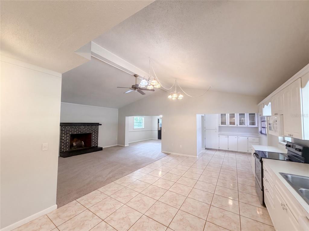 An open-concept kitchen with tiled floors flows into a carpeted living area with a fireplace — 1870 N SEMINOLE ROAD, AVON PARK, FL
