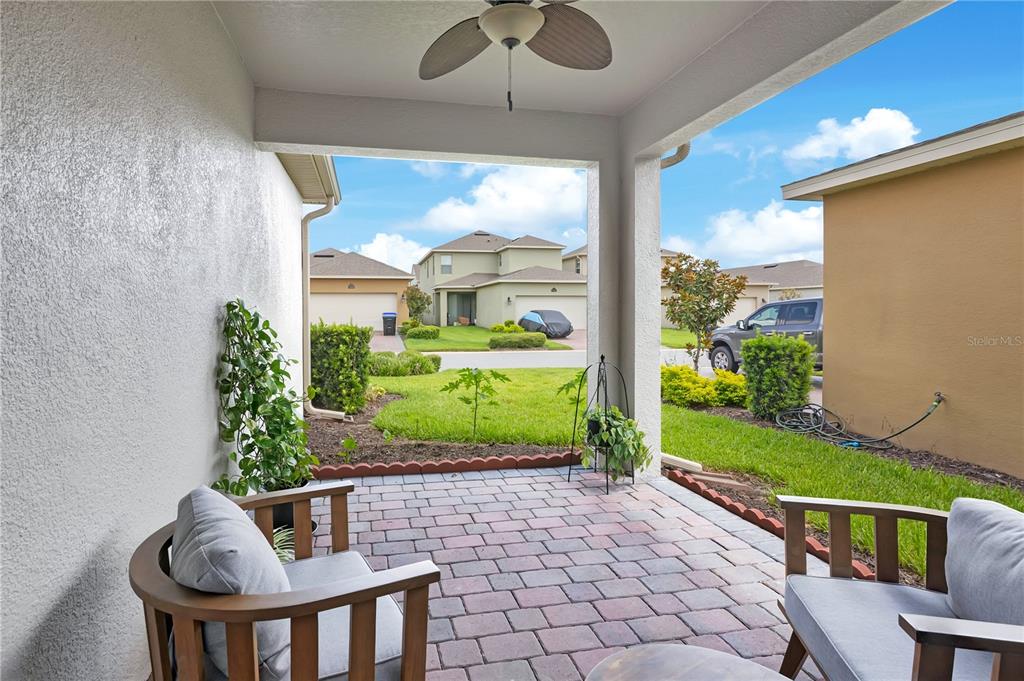 A covered patio features a brick paver floor, a ceiling fan, and two wooden chairs — 16802 OAKBORO STREET, WINTER GARDEN, FL