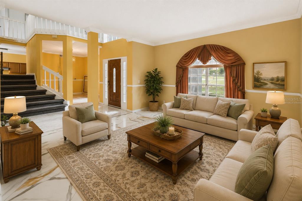 A living room with marble floors, a staircase, and a large arched window with curtains — 6415 ABBEYDALE COURT, ORLANDO, FL