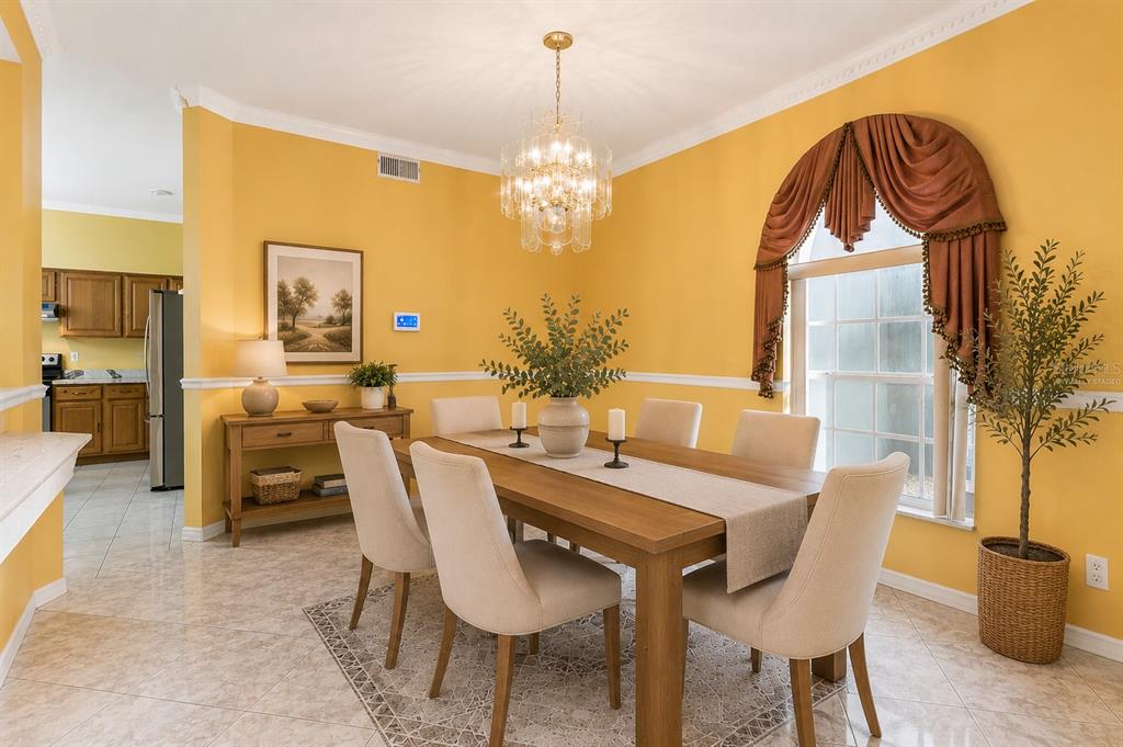 A dining room with yellow walls, a wooden table, six chairs, and a crystal chandelier — 6415 ABBEYDALE COURT, ORLANDO, FL