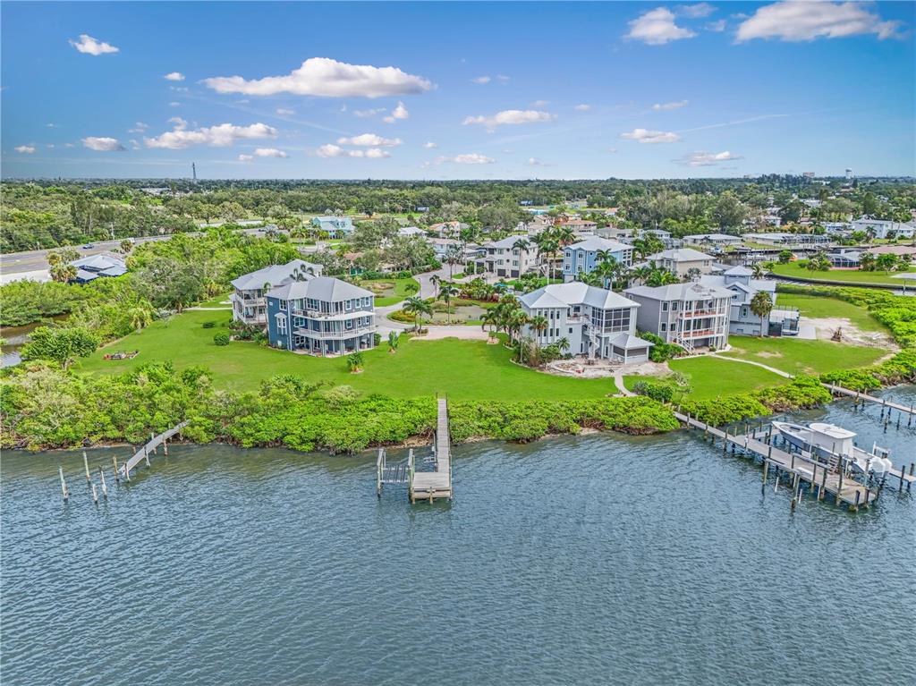 An elevated three-story house with a dock, patio, and fire pit overlooking the water — 5539 2ND AVENUE CIRCLE W, PALMETTO, FL