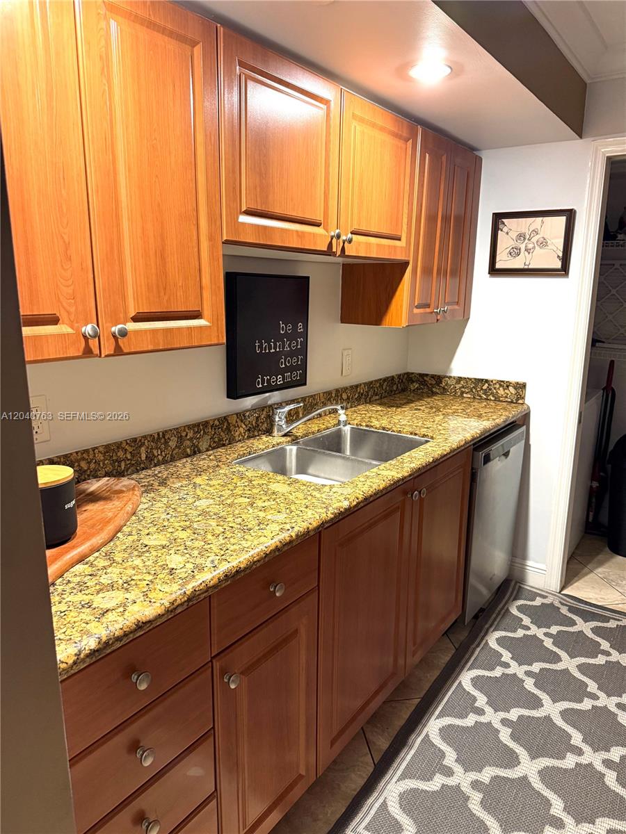A kitchen features wood cabinets, granite countertops, a double sink, and a stainless steel dishwasher — 6917 Collins Ave # 506, Miami Beach FL 33141, MIAMI BEACH, FL