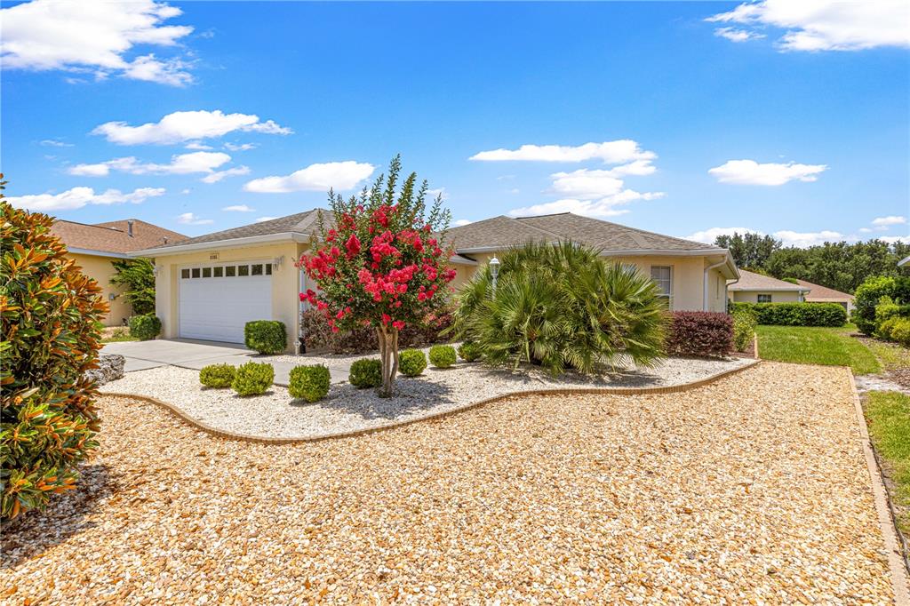 A single-story house with a white garage, gravel landscaping, and a flowering tree in front — 8086 SW 81ST LOOP, OCALA, FL