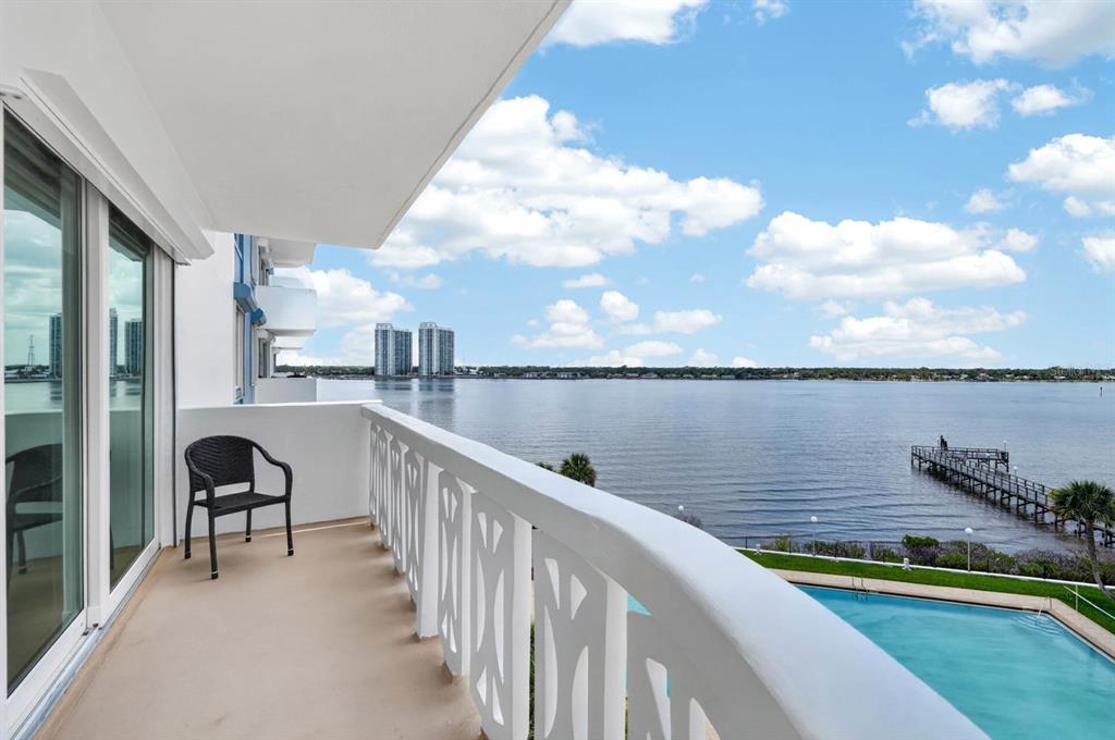 A balcony with a chair overlooks a swimming pool, a pier, and a large body of water — 925 N HALIFAX AVENUE UNIT 403, DAYTONA BEACH, FL