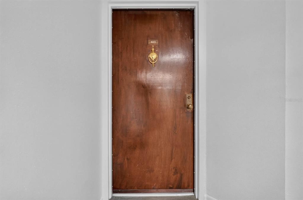 A wooden apartment door with a brass knocker and the number 403 — 925 N HALIFAX AVENUE UNIT 403, DAYTONA BEACH, FL