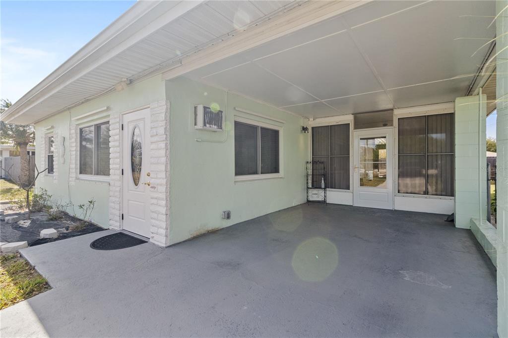 A light green house exterior features a covered concrete carport and a white front door — 4419 MELBOURNE STREET, PUNTA GORDA, FL