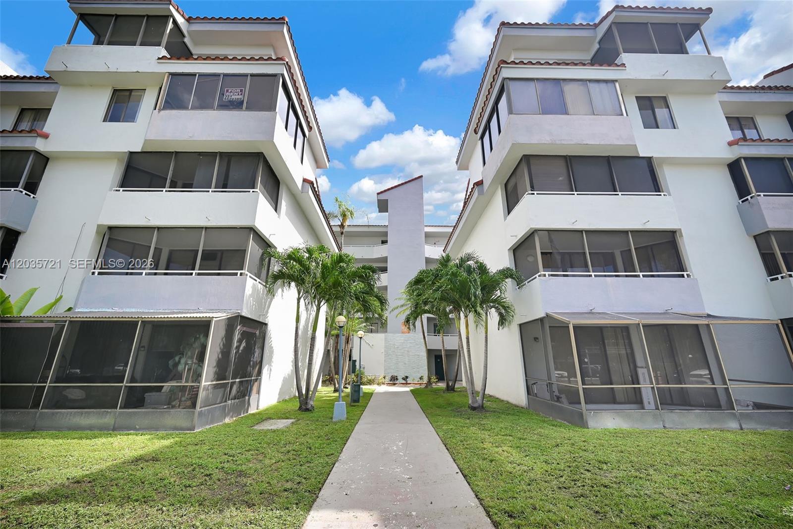 A walkway leads between two multi-story apartment buildings with screened balconies and palm trees — 8255 SW 152nd Ave # 312, Miami FL 33193, MIAMI, FL