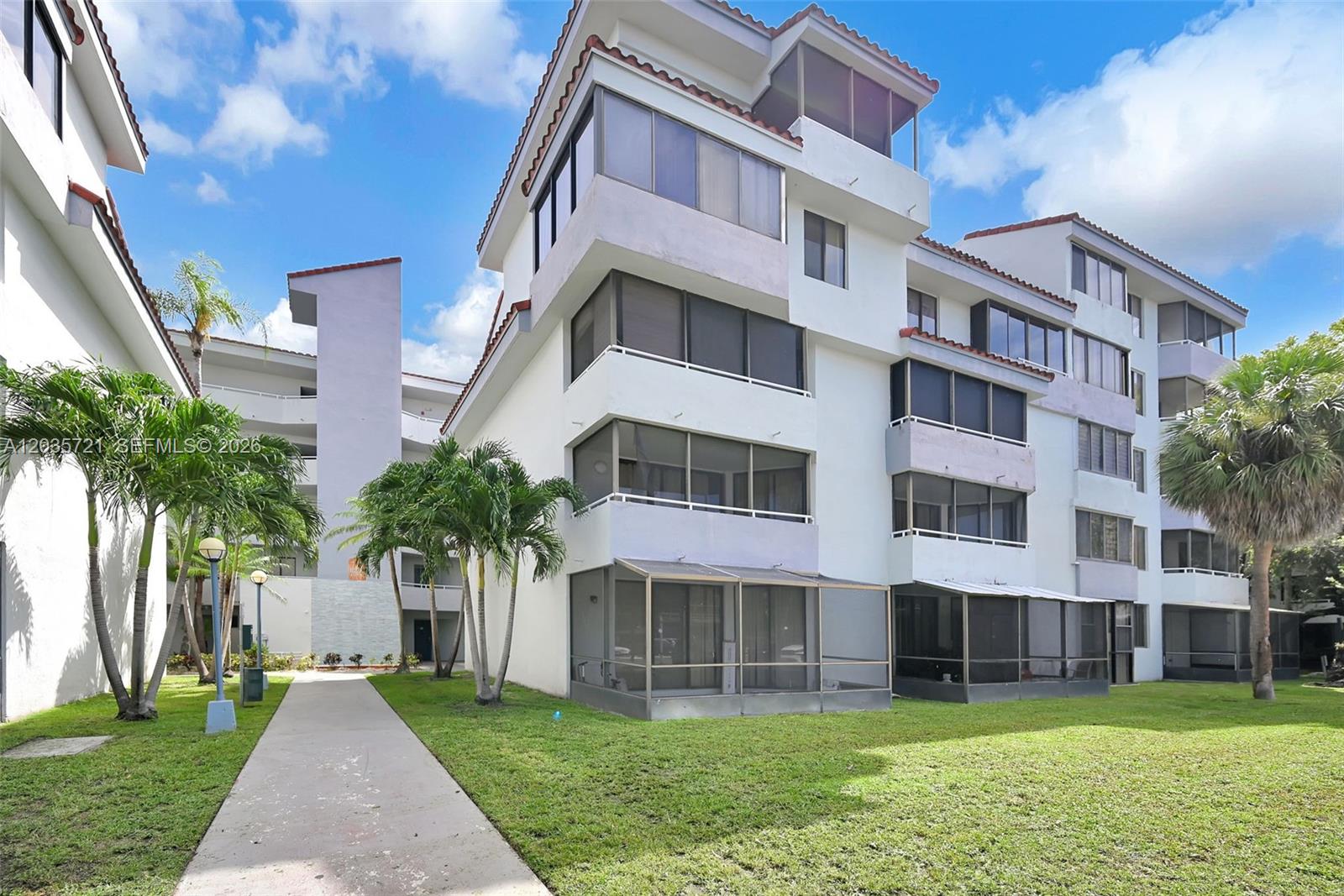 A multi-story residential building with screened balconies and palm trees on a grassy lawn — 8255 SW 152nd Ave # 312, Miami FL 33193, MIAMI, FL