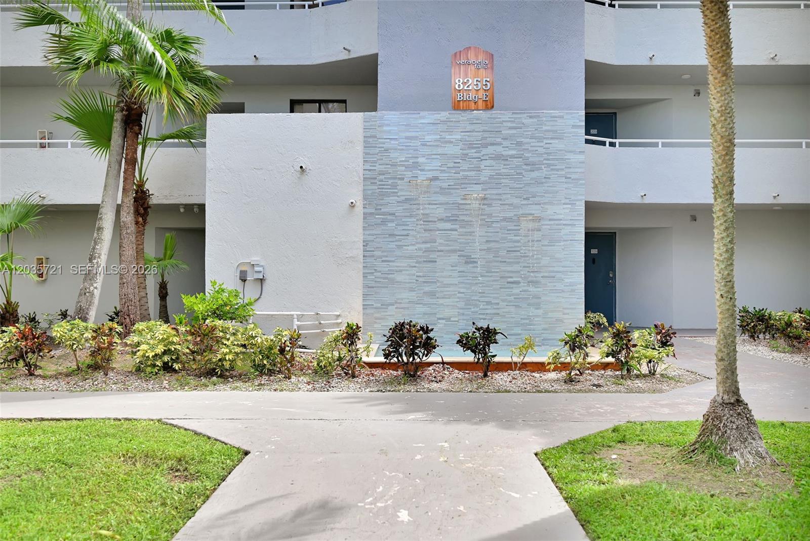 A multi-story apartment building exterior features a central water feature and a paved walkway — 8255 SW 152nd Ave # 312, Miami FL 33193, MIAMI, FL