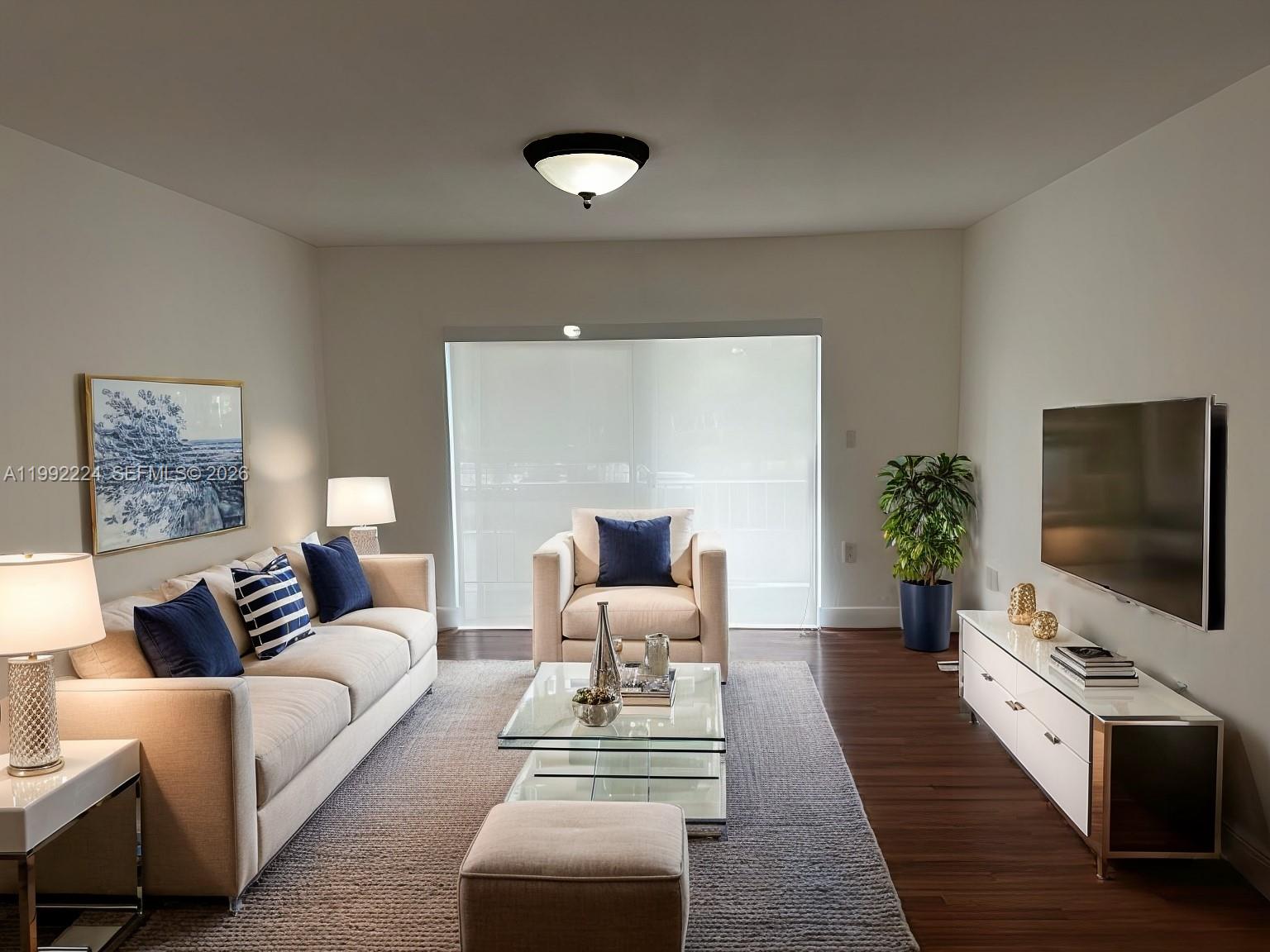 A living room features a beige sofa, armchair, glass coffee table, and wall-mounted television — 5400 SW 77 Court # 2R, Miami FL 33155, MIAMI, FL