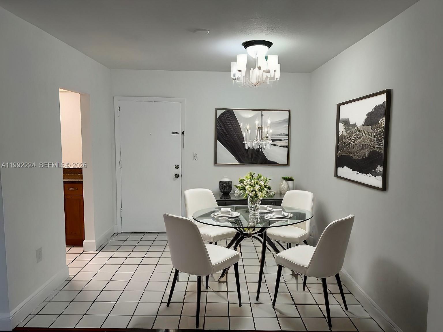 A dining area features a glass table, four white chairs, and a modern chandelier — 5400 SW 77 Court # 2R, Miami FL 33155, MIAMI, FL