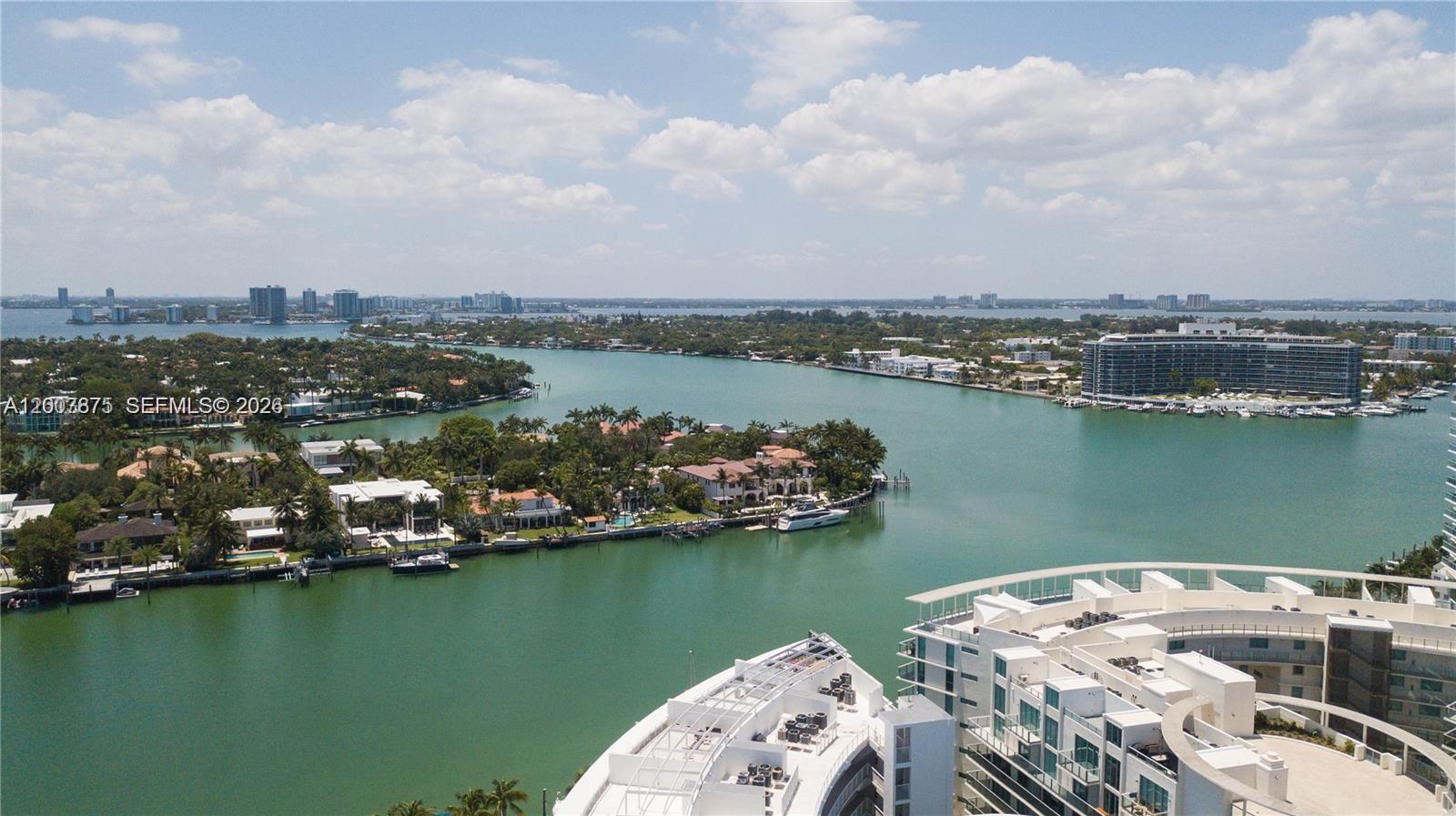An aerial view shows a waterway surrounded by luxury waterfront homes and modern apartment buildings — 6515 Collins Ave # 1609, Miami Beach FL 33141, MIAMI BEACH, FL