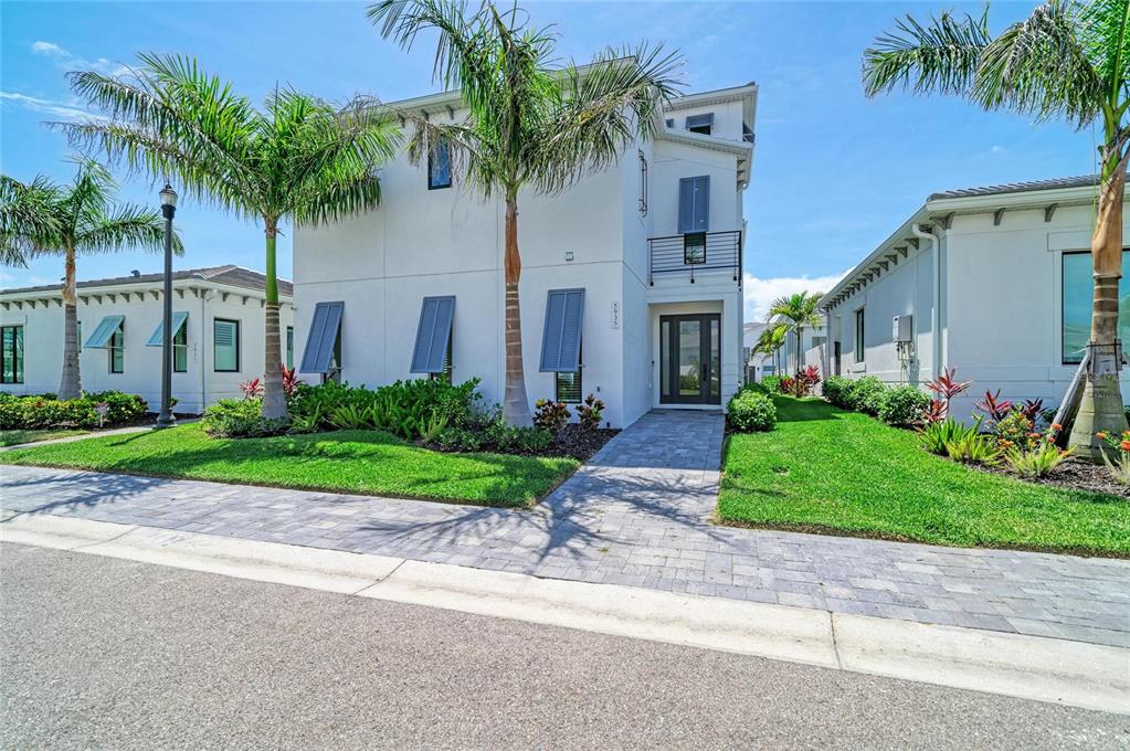 A two-story white house with palm trees, a paved walkway, and blue shutters — 5935 CAT CLAW LANE, BRADENTON, FL