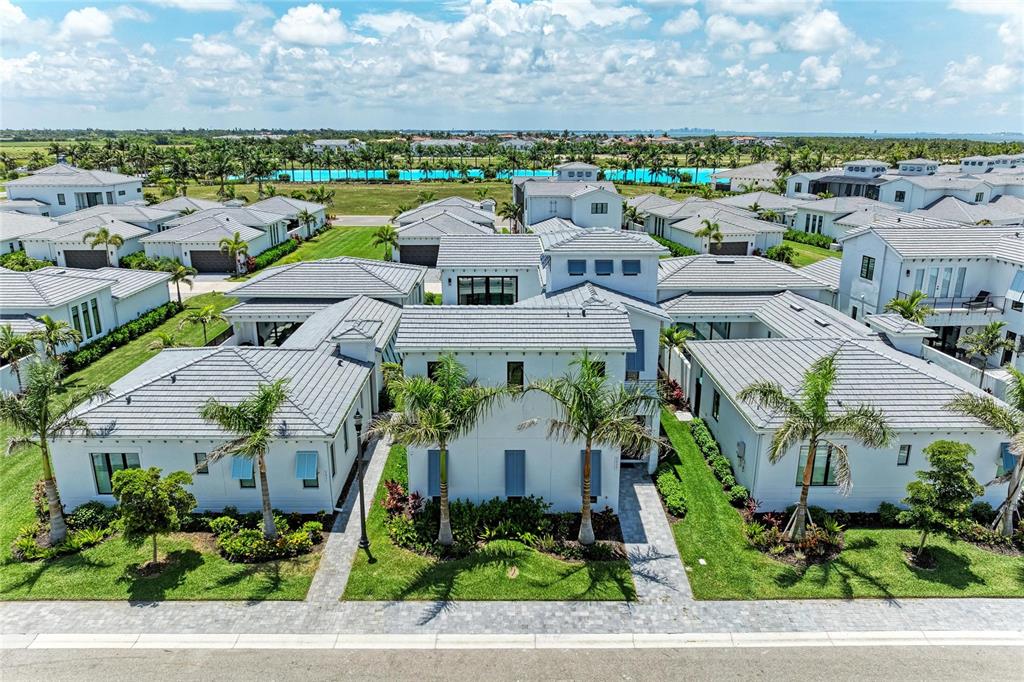 An aerial view of a modern white house with a gray tile roof and palm trees — 5935 CAT CLAW LANE, BRADENTON, FL