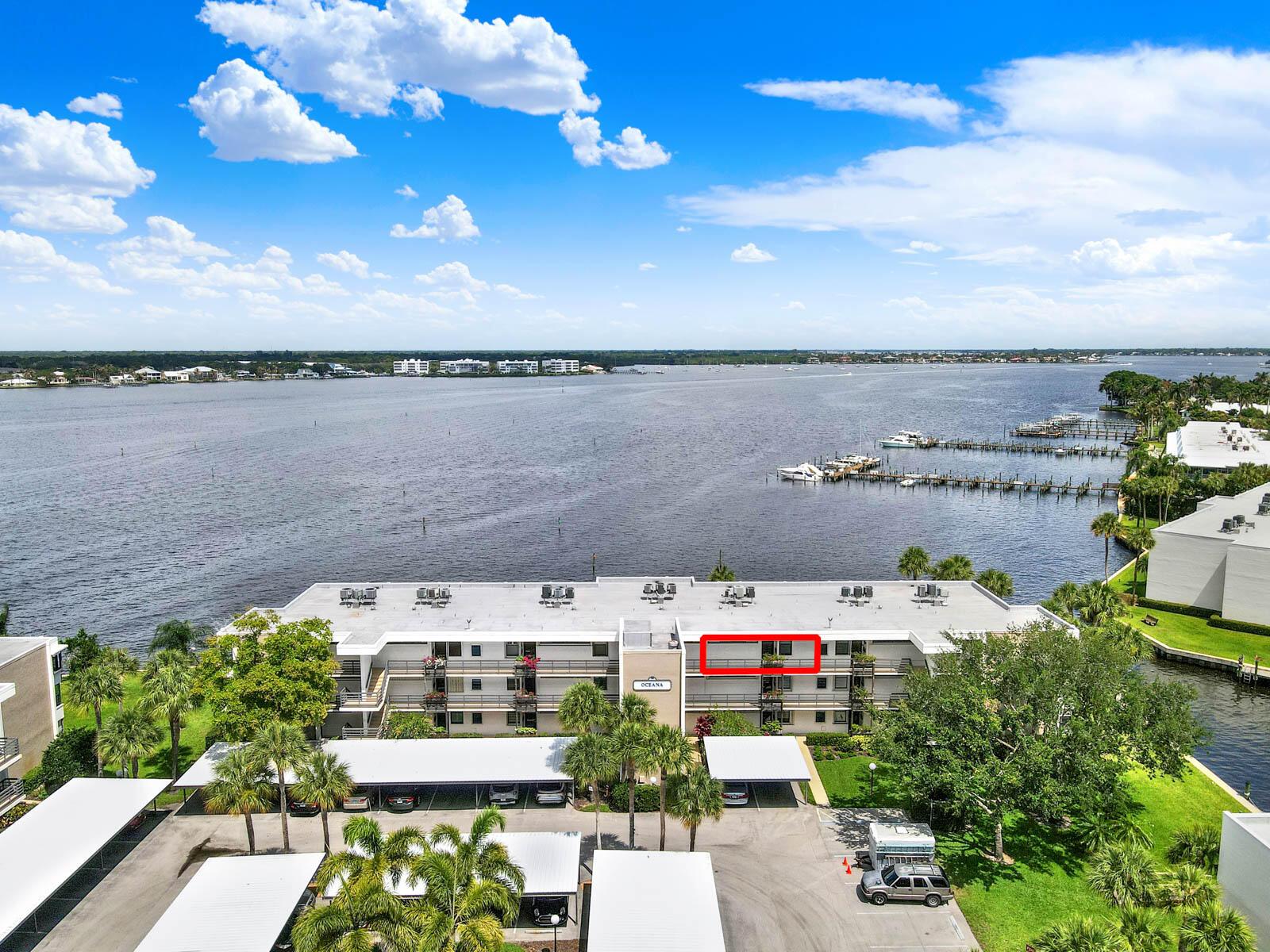 An aerial view shows a multi-story apartment building with a red-outlined balcony overlooking water — 1950 SW Palm City Road # 305, Stuart FL 34994, STUART, FL