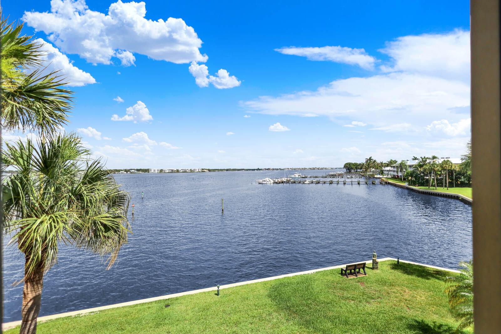 A view of a calm river from a balcony overlooking a grassy lawn and dock — 1950 SW Palm City Road # 305, Stuart FL 34994, STUART, FL