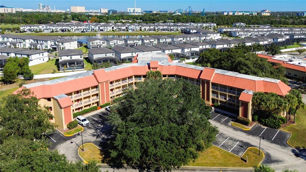 An aerial view shows a multi-story building with a red tile roof and parking lot — 6337 PARC CORNICHE DRIVE UNIT 2304, ORLANDO, FL