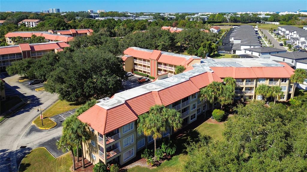 An aerial view shows multi-story apartment buildings with orange tile roofs and surrounding trees — 6337 PARC CORNICHE DRIVE UNIT 2304, ORLANDO, FL