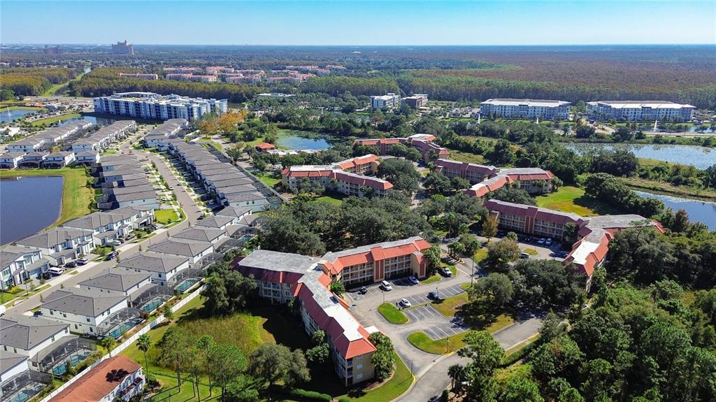 An aerial view shows a residential complex with multi-story apartment buildings and rows of townhomes — 6337 PARC CORNICHE DRIVE UNIT 2304, ORLANDO, FL