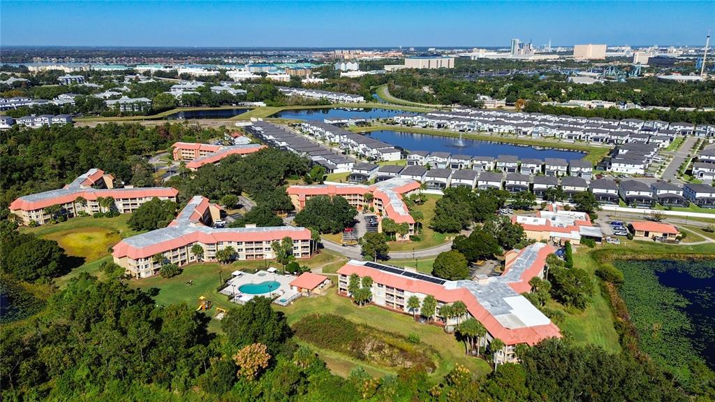 An aerial view shows multi-story apartment buildings with red roofs, a swimming pool, and ponds — 6337 PARC CORNICHE DRIVE UNIT 2304, ORLANDO, FL
