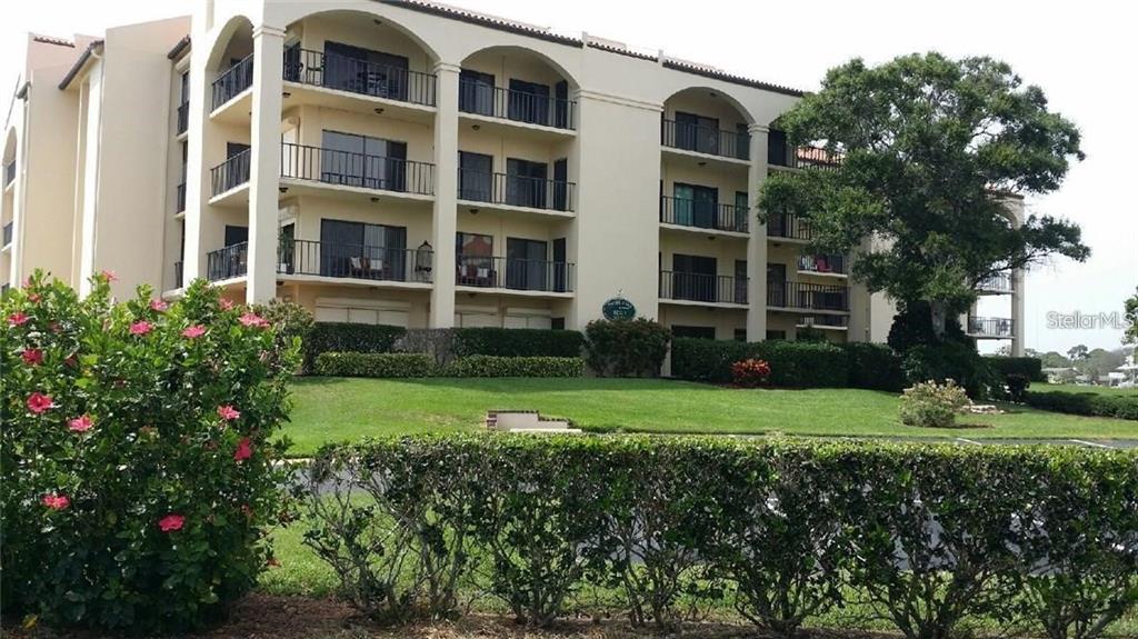A multi-story beige apartment building features arched balconies and is surrounded by landscaped grounds — 328 MARINER DRIVE UNIT 328, TARPON SPRINGS, FL