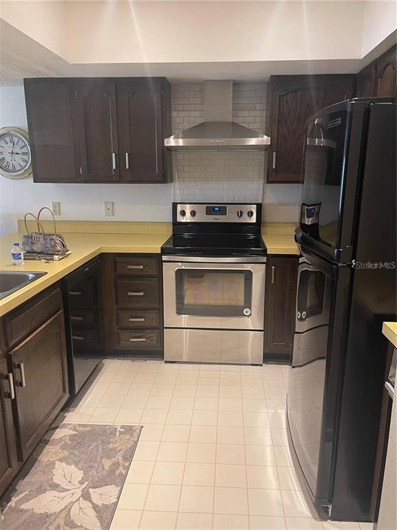 A kitchen features dark wood cabinets, yellow countertops, stainless steel appliances, and white tile flooring — 328 MARINER DRIVE UNIT 328, TARPON SPRINGS, FL